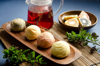 Flakey pastries filled with Sesame, Red Yeast Rice, Green Tea, Sweet Potato mochi on wooden plate