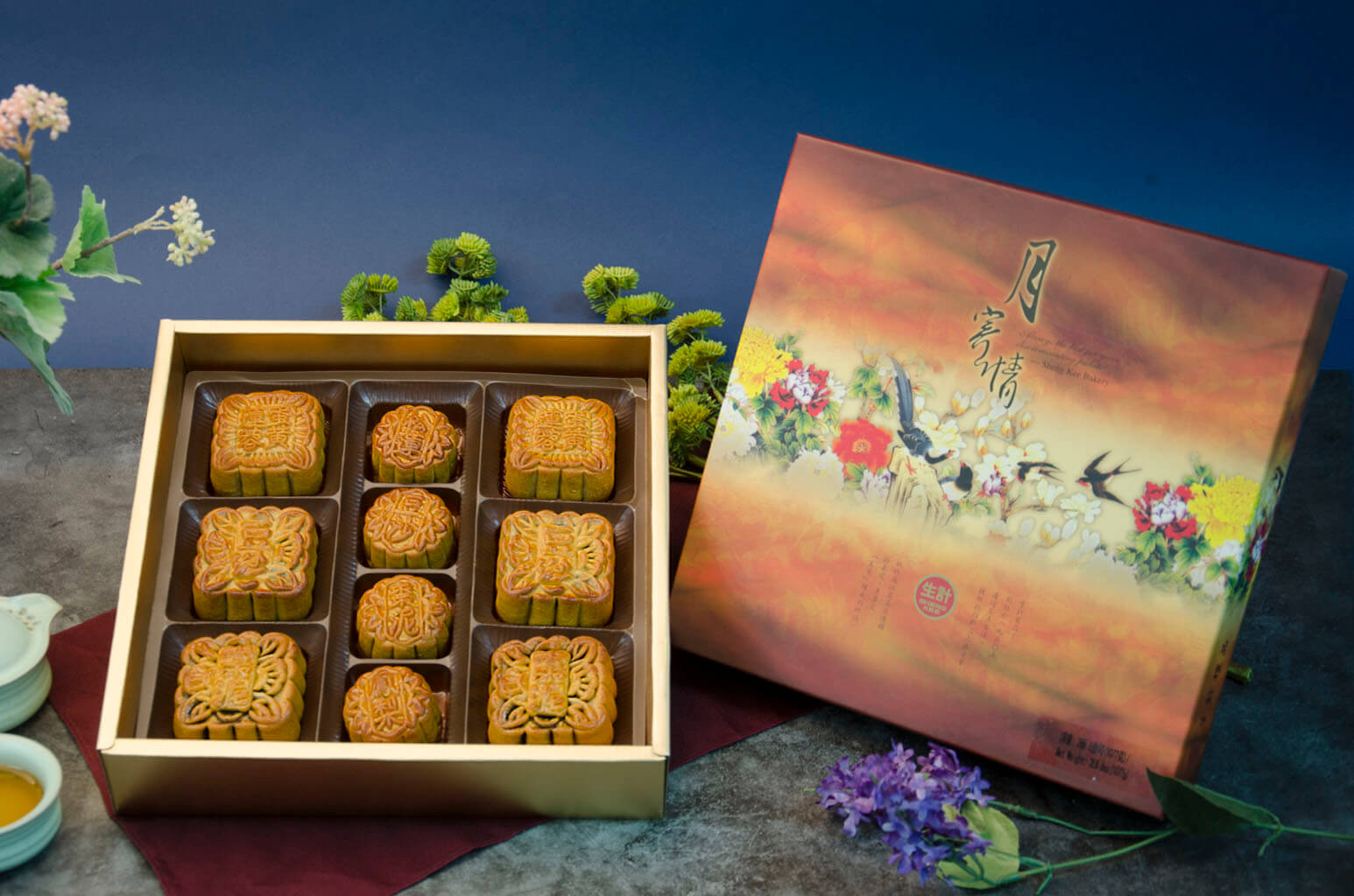 An assorted gift box of mooncakes with six medium and four small mooncakes, displayed in a decorative box with floral  designs.