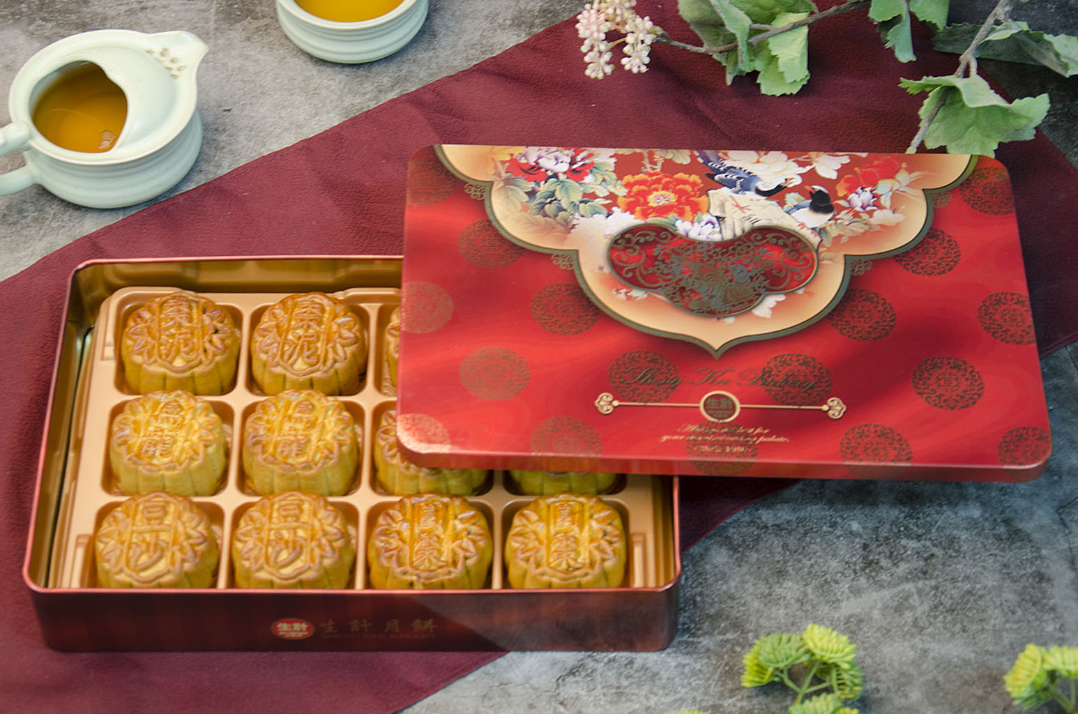 A Gift Box of 12 Assorted Small Mooncakes, with 6 Different Flavors. In a red decorative tin on red fabric.