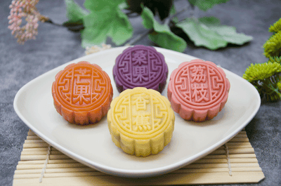 Mulberry, Banana, Lychee, Mango Mooncakes on a white plate on bamboo