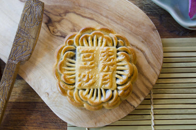 A Large Red Bean Double Yolk Mooncake on a wooden board.