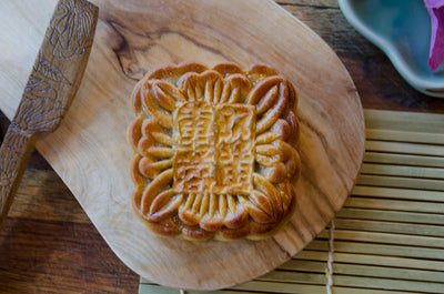 A Large Lotus Double Yolk Mooncake on a wooden board.