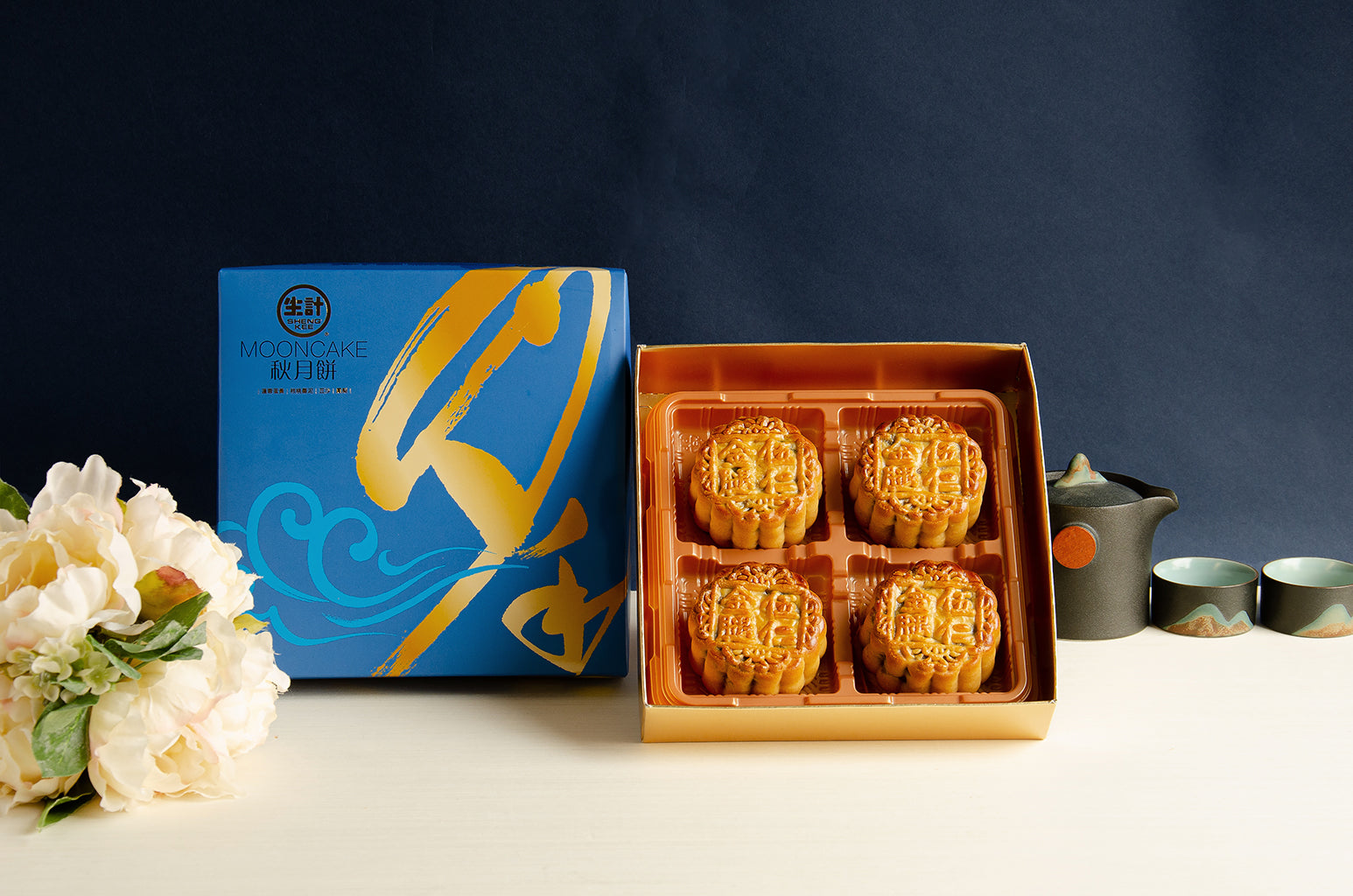 A set of four golden-brown mooncakes with a mix of nuts and ham, presented in a box with a floral design.