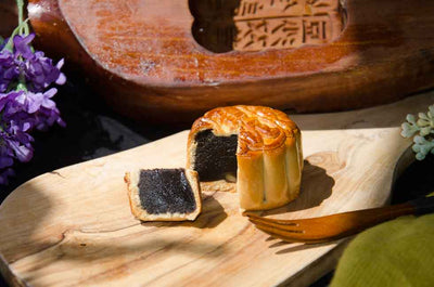 Small Date Mooncake cut to see filling on wooden board.